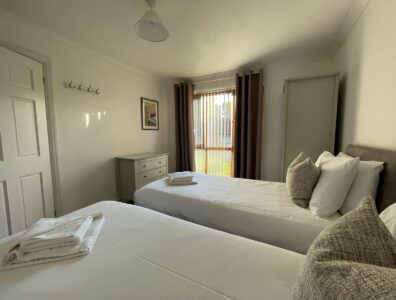 Twin beds in a spacious bright room with well matched curtains, pillows and cusions
